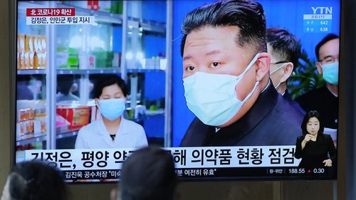 People in Seoul watch a news broadcast showing Kim Jong-un. Kim has blamed South Korea for his country's COVID-19 outbreak.