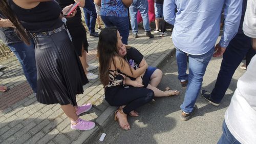 Women sit in an embrace outside the "Cantinho do Bom Pastor" daycare centre after a fatal attack on children, in Blumenau, Santa Catarina state, Brazil, Wednesday, April 5, 2023.