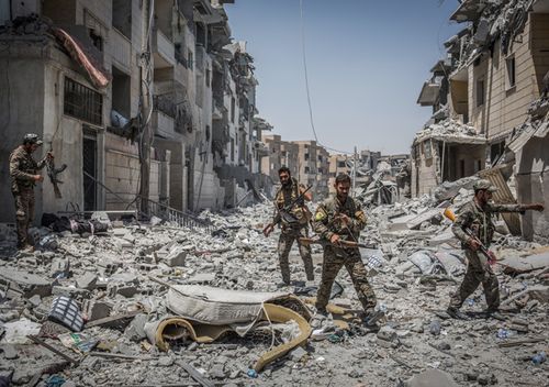 Soldiers of the Syrian Democratic Forces (SDF) move through debris at the front line in the Al Dariya neighborhood in western Raqqa, Syria, 24 July 2017. (AFP)