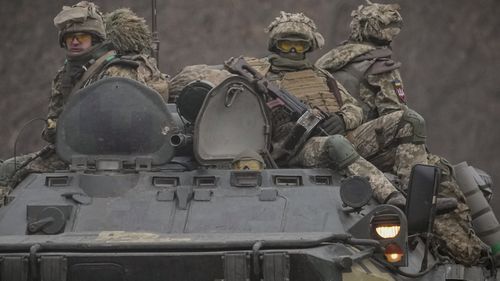 Ukrainian servicemen sit atop armored personnel carriers driving on a road in the Donetsk region, eastern Ukraine.