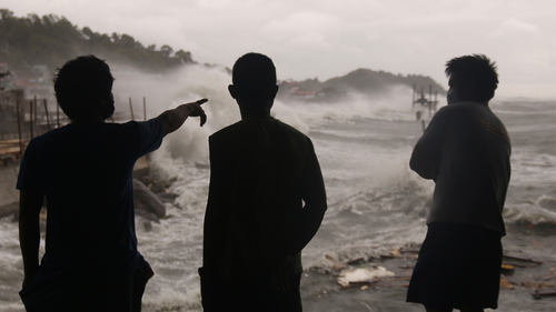 Men watch as strong waves caused by typhoon Vongfong batter the coastline of Catbalogan city, Western Samar province, eastern Philippines on Thursday May, 14, 2020. 