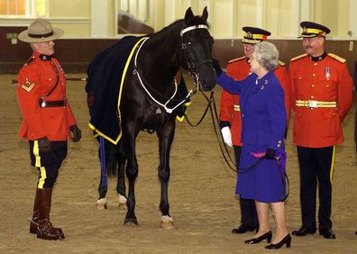 Queen Elizabeth pats James,  the horse that presented as a gifted to the Queen by members of the Royal Canadian Mounted Police in 1998.