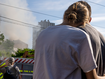 A couple embrace as they look at smoke billowing the air from residential buildings following explosions, in Kyiv, Ukraine, Sunday, June 26, 2022.