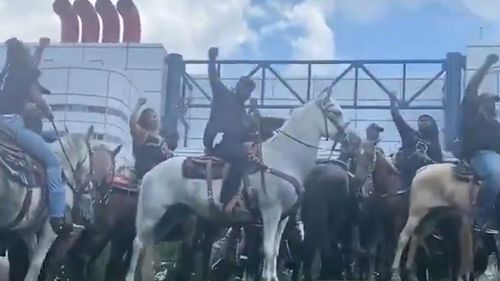 Horsemen and women raise their arms in solidarity for George Floyd.
