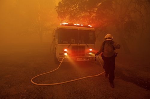 A firefighter rushes to save a home as the River Fire tears through Lakeport, Calif., on Tuesday, July 31, 2018. The residence eventually burned. (AP Photo/Noah Berger)