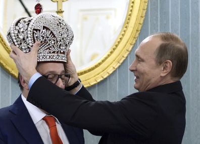 Russian President Vladimir Putin puts a replica of the Imperial Crown on comedian Gennady Khazanov during a Kremlin meeting marking Khazanov's 70th birthday, in Moscow, Russia, Tuesday, Dec. 1, 2015.