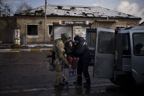 A Ukrainian soldier helps an elderly woman who was being evacuated on a shopping cart from Irpin, in the outskirts of Kyiv, Ukraine, Tuesday, March 8, 2022 