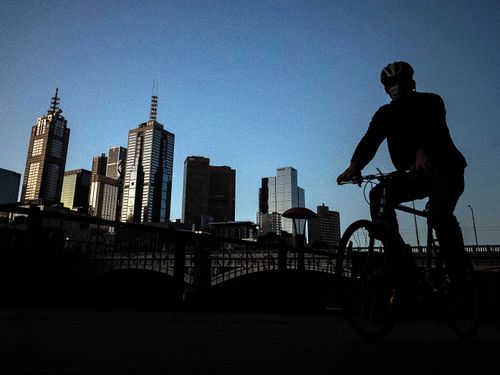 A man rides his bike along a very quiet Southbank in Melbourne, Australia.