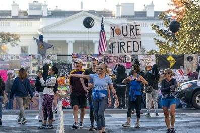 People gather on Black Lives Matter Plaza on the north side of the White House where a tall metal security fence has been covered in protest signs