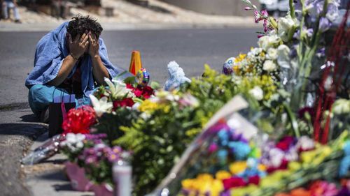 An El Paso man weeps beside a makeshift memorial for victims of the Wal-Mart massacre.