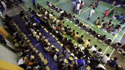 Rohingya refugees line up for breakfast in the sport stadium of Lhok Sukon, North Aceh. (AAP)
