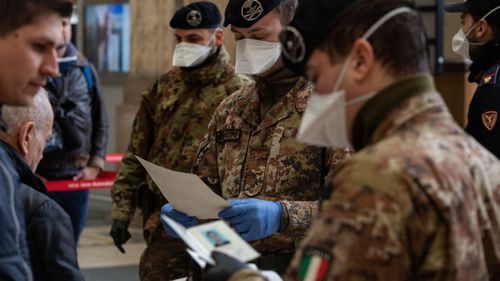 Police officers and soldiers check passengers leaving from Milan's main train station after travel was canceled except for work and health reasons.