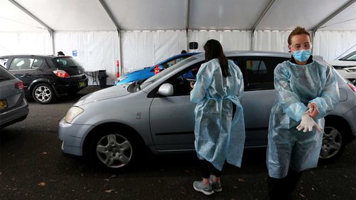 Healthcare workers consult with clients attending the Belmore Sports Ground vaccination hub in Sydney.