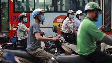 People wear face masks in hopes of curbing the spread of the coronavirus riding mopeds in Hanoi, Vietnam.