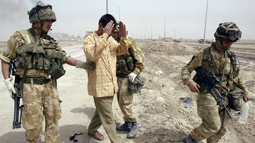 An Iraqi soldier wearing civilian clothes gives himself up to British soldiers in the southern Iraqi town of Basra, 31 March 2003.