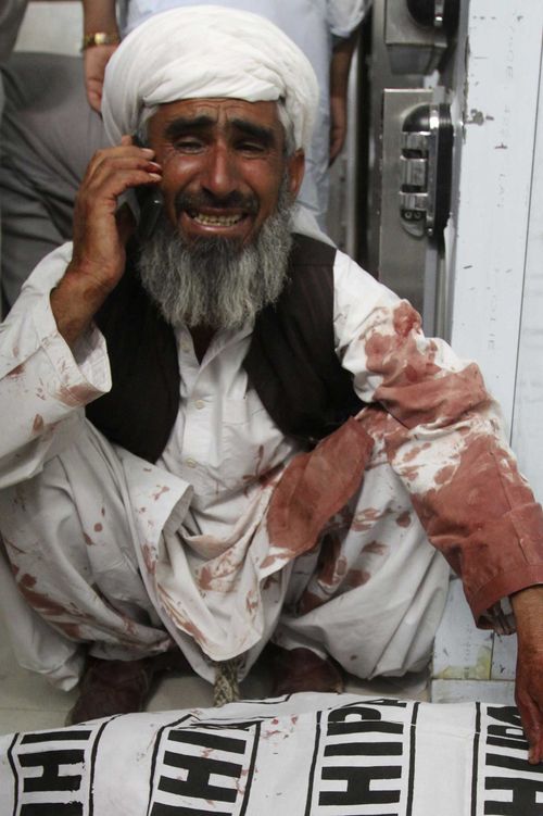 A Pakistani man weeps while crouching above the body of a family member after a bombing in Quetta. (AAP)