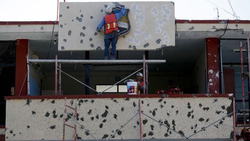 Workers repair the facade of City Hall riddled with bullet holes in Villa Union.
