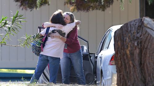 Two women embrace outside Rancho Tehama Elementary School, where a gunman opened fire. (AAP)