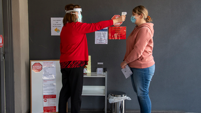 A patient has her temperature checked before a medical clinic during lockdown due to the continuing spread of the coronavirus in Melbourne, Thursday, Aug. 6, 2020. (AP Photo/Andy Brownbill)