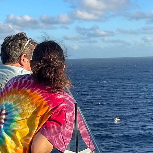 A boat of migrants is seen from an upper deck of the Celebrity Beyond cruise ship.