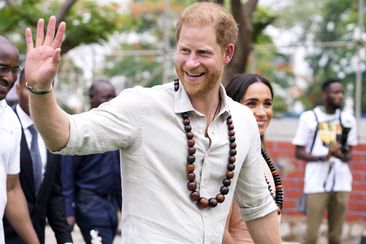 Prince Harry gestures as he and Meghan visit children at the Lights Academy in Abuja, Nigeria, Friday, May 10, 2024.   