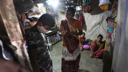 Mina Ramesh Jakhawadiya, center, tells her son Ritik Ramesh, left, not to go out and play because of the coronavirus and be in the house in Mumbai, India, March 30, 2020. Jakhawadiya makes a living selling cheap plastic goods with her husband on the streets of Mumbai. For her, the order means 21 days in a 6-by-9 foot room with five people, no work, a couple days of food and very less cash. (AP Photo/Rafiq Maqbool)