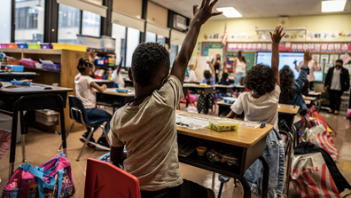 A child raises his hand in class on the first day of school at Bayview Avenue School of Arts and Sciences in Freeport, New York on September 1, 2021.