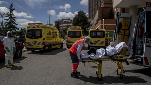 An emergency worker wearing a face mask transports an elderly patient to an ambulance at the 12 Octubre hospital in Madrid, Spain, Spain, Thursday April 30, 2020 as the lockdown to combat the spread of coronavirus continues
