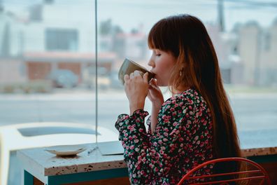 Stock photo of woman drinking coffee at a cafe.