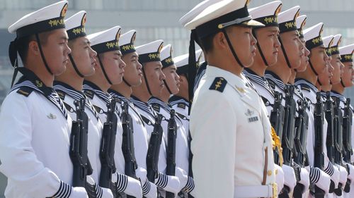 Chinese People's Liberation Navy sailors stand in formation on the deck of a type 054A guided missile frigate 'Wuhu'.