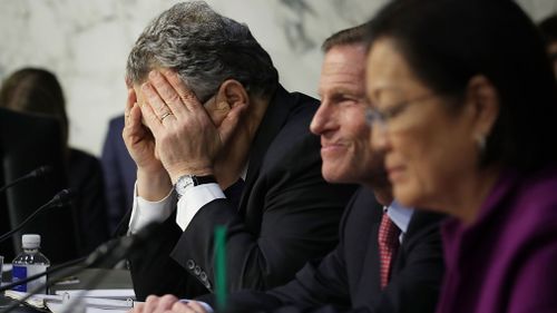 Judiciary Committee member Senator Al Franken covers his face in frustration as he questions witnesses from Google, Facebook and Twitter. (Getty)