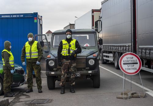 Lithuanian border guards stand next to trucks stuck in traffic jams for 60 kilometres (36 miles) on Lithuanian side to enter Poland through Kalvarija-Budzisko check point,