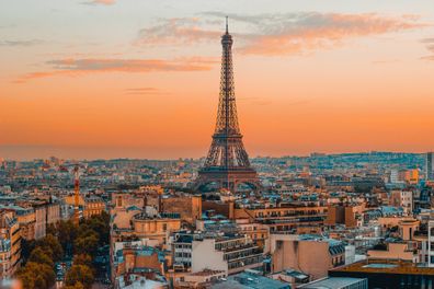 Breathtaking view of the Eiffel Tower and the serene Paris skyline during a vibrant European sunset, captured from the top of the Arc de Triomphe.