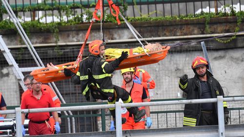 Rescue workers lift a person out of the rubble of the collapsed bridge.