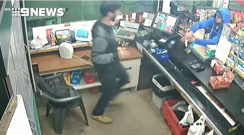 The cashier steps back after the man lunges at him with the knife.