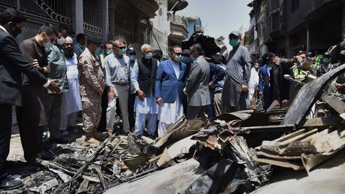In this photo released by Pakistan Civil Aviation Authority, provincial governor Imran Ismail, center, in blue coat, and Pakistan's aviation minister Ghulam Sarwar, center in black waistcoat, visit the site of Friday's plane crash, in Karachi, Pakistan, Saturday, May 23, 2020