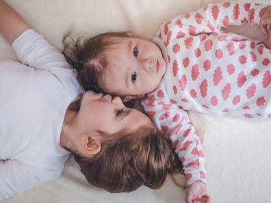 Baby and toddler sister lying together