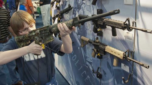 A boy looks at an assault rifle at an NRA convention. (AAP)