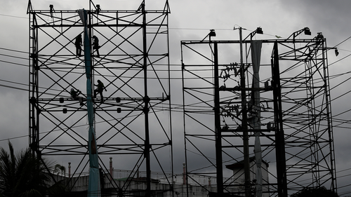 Dark clouds envelop the skies as workers fold a billboard to prepare for the coming of typhoon Vongfong, locally named Ambo, in Metro Manila, Philippines on Thursday May, 14, 2020. 