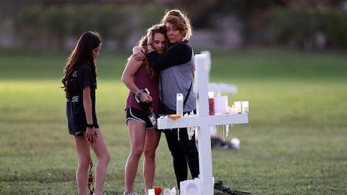 People hug as they pay homage at the memorial crosses, for the 17 deceased students and faculty at Marjory Stoneman Douglas High School. (AAP)