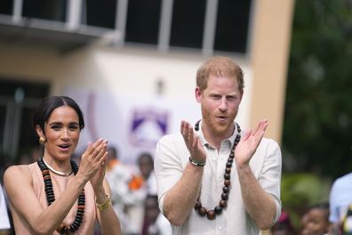 Prince Harry and Meghan gesture as they visit children at the Lights Academy in Abuja, Nigeria, Friday, May 10, 2024.   
