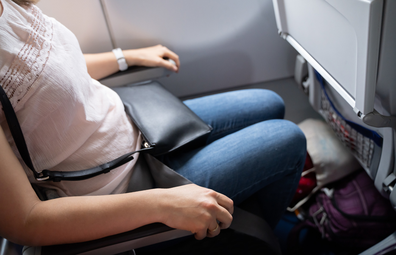 Woman in plane window seat using both armrests