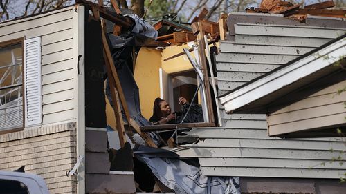 A woman collects belongings from a family members home after the roof was ripped off from a tornado on Oakview Drive in North Little Rock, Ark. Friday, March 31, 2023.