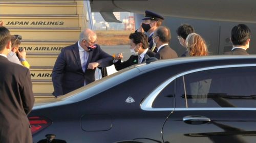 Australian Prime Minister Scott Morrison elbow bumps a Japanese official after landing in Japan for talks.