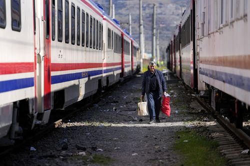 A man walks between trains using as shelters, in Iskenderun city, southern Turkey, Tuesday, Feb. 14, 2023.