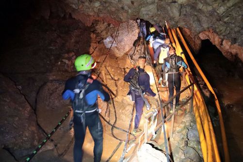 In this handout photo released by Thai Navy, Saturday, July 7, 2018, Thai rescue teams walk inside cave complex where 12 boys and their soccer coach went missing in Mae Sai, Chiang Rai province, northern Thailand. Chiang Rai Gov. Narongsak Osatanakorn says authorities are waiting for two big groups of volunteer divers to arrive later Saturday and Sunday, after which they'll be ready to begin the operation of bringing them out. (Thai Navy via AP)