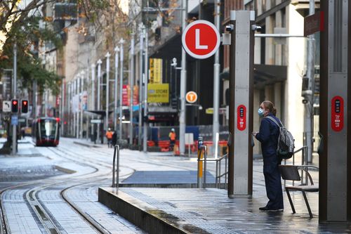 A frontline worker awaits the a tram on George Street in Sydney amid the city-wide lockdown. Sydney lockdown