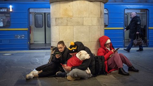 People sit in the subway station being used as a bomb shelter during a rocket attack in Kyiv, Ukraine, Thursday, Dec. 29, 2022. 
