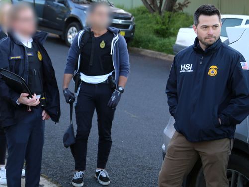 An official with US Homeland Security is pictured NSW Police and Australian Border Force officers as a search warrant was executed on the property.