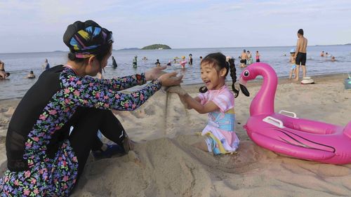A girl and her mother play on the beach at the the Wonsan-Kalma resort in Wonsan, Kangwon Province, North Korea, Tuesday, July 1, 2025. (AP Photo/Jon Chol Jin)